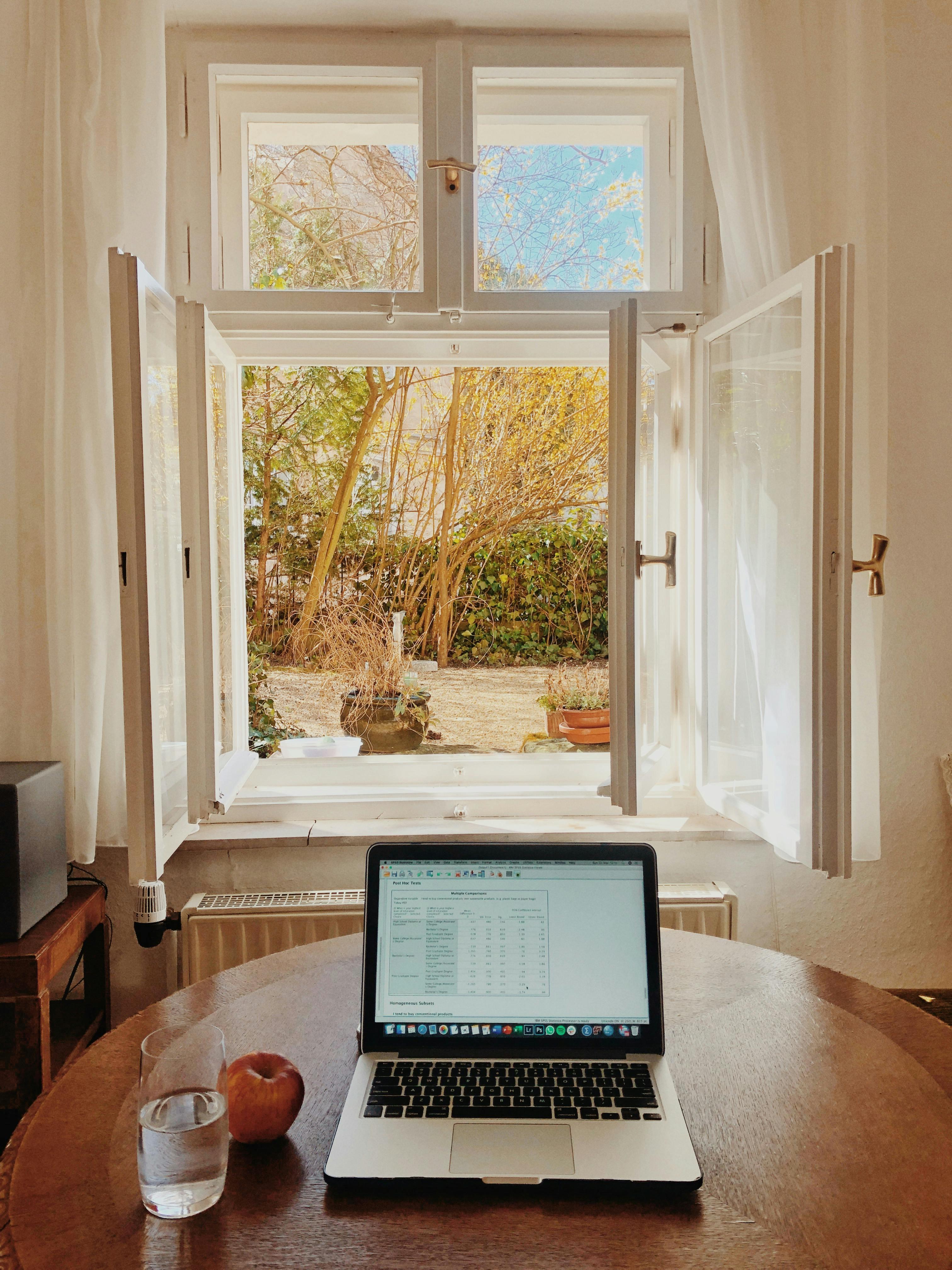 A clean desk with a macbook and a glass of water